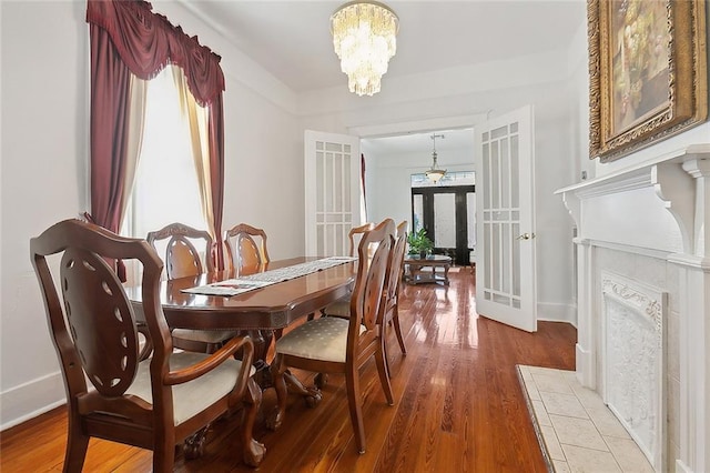 dining space featuring french doors, wood-type flooring, and a notable chandelier