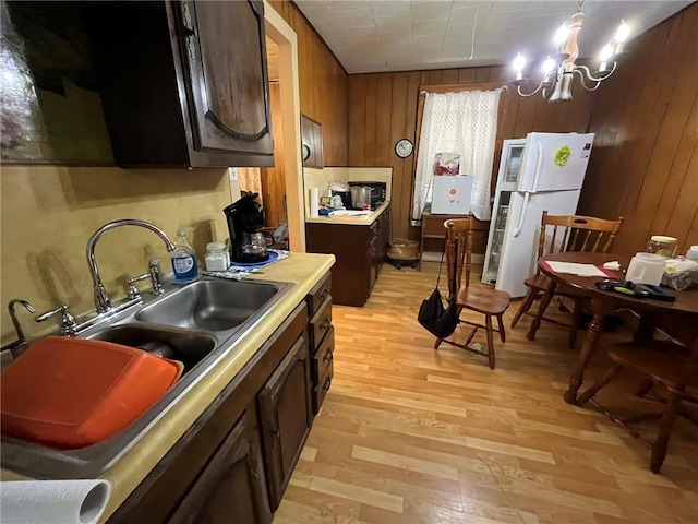 kitchen with white refrigerator, light hardwood / wood-style floors, dark brown cabinetry, and a notable chandelier