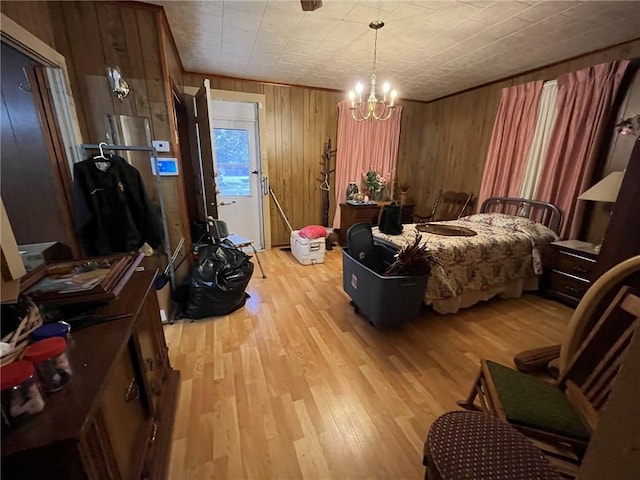 bedroom with an inviting chandelier, light hardwood / wood-style flooring, and wood walls