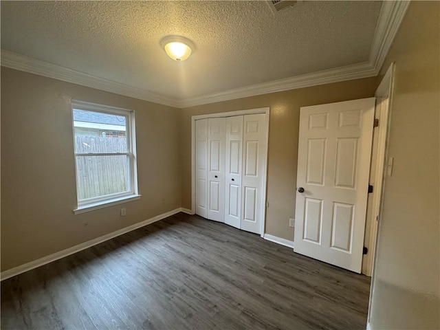 unfurnished bedroom featuring a textured ceiling, ornamental molding, dark wood-type flooring, and a closet