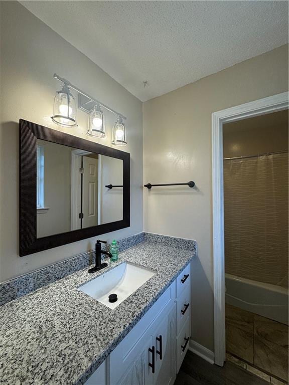 bathroom featuring vanity, hardwood / wood-style floors, a textured ceiling, and shower / bathtub combination with curtain