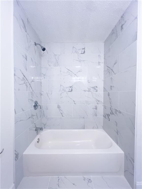 bathroom featuring tiled shower / bath combo and a textured ceiling