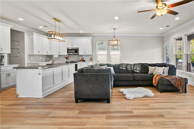 living room featuring crown molding, ceiling fan with notable chandelier, light hardwood / wood-style floors, and sink