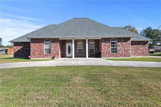 view of front of house featuring a shingled roof, a front lawn, and brick siding