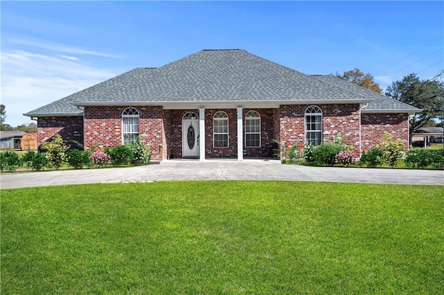 view of front of house with brick siding, a shingled roof, and a front yard