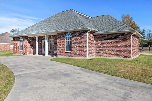 ranch-style home featuring a front lawn, roof with shingles, and brick siding