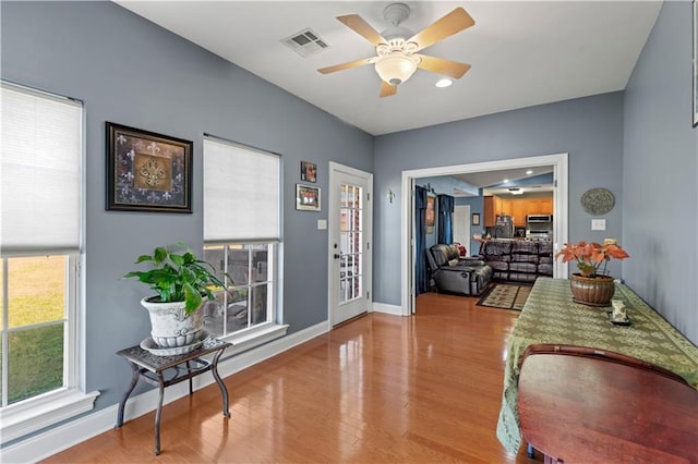 interior space featuring ceiling fan, baseboards, wood finished floors, and visible vents