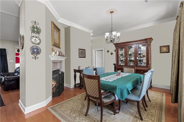 dining space featuring a tile fireplace, wood finished floors, and a notable chandelier