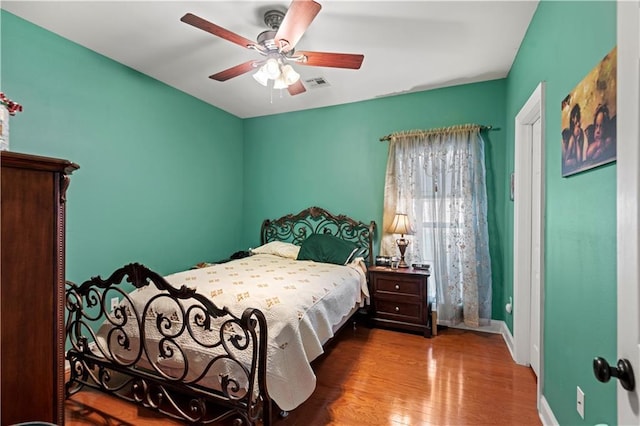 bedroom featuring baseboards, wood finished floors, visible vents, and a ceiling fan