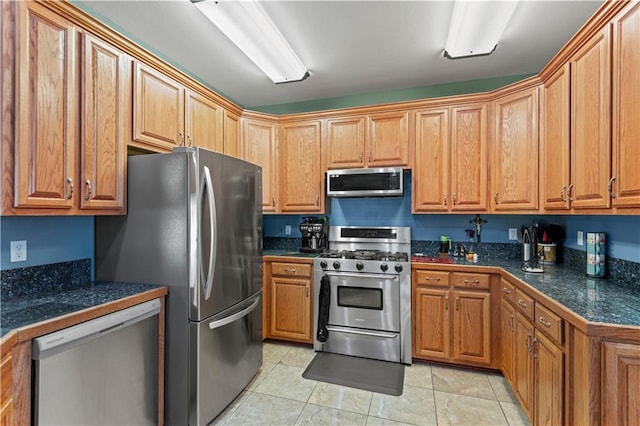 kitchen featuring tile countertops, brown cabinetry, appliances with stainless steel finishes, and light tile patterned floors