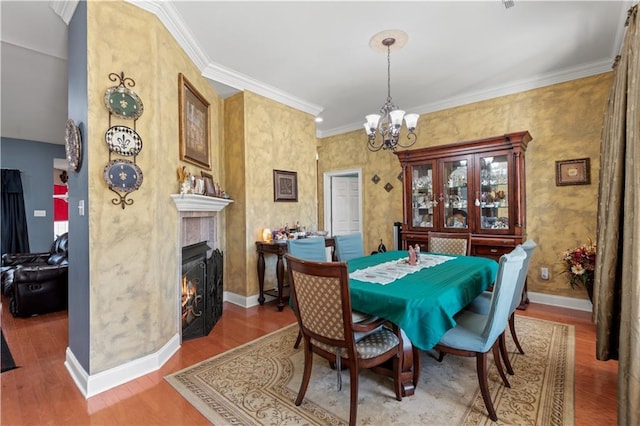 dining space featuring an inviting chandelier, ornamental molding, wood finished floors, and baseboards