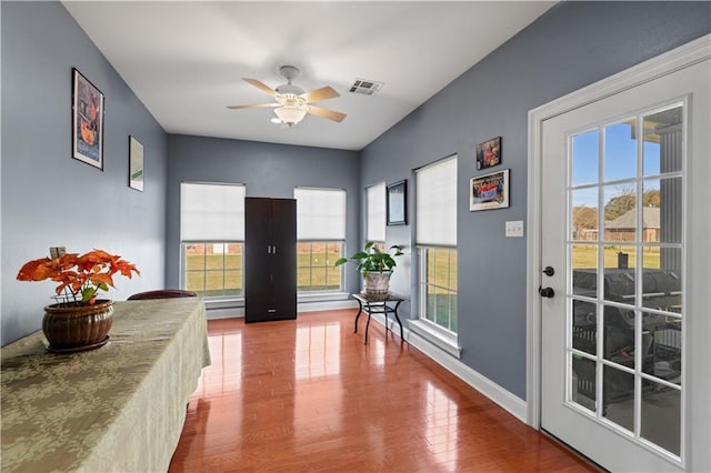 doorway with a ceiling fan, wood finished floors, and plenty of natural light