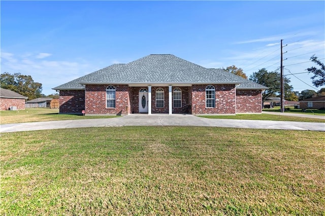 ranch-style house with a front lawn, brick siding, roof with shingles, and curved driveway