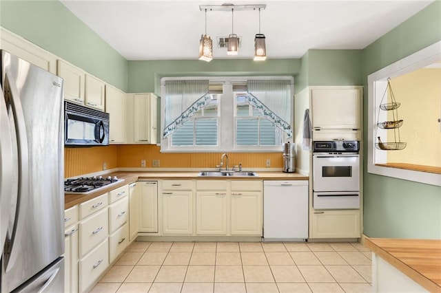 kitchen featuring decorative light fixtures, sink, light tile patterned floors, and stainless steel appliances