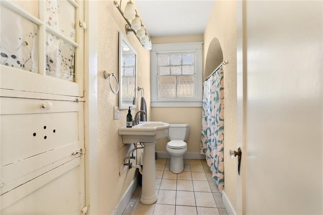 bathroom featuring tile patterned flooring, a shower with shower curtain, and toilet