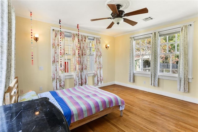 bedroom with hardwood / wood-style flooring, ceiling fan, and crown molding