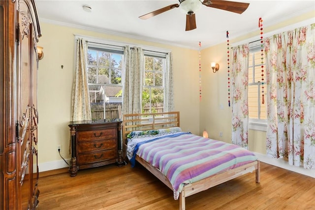 bedroom with light hardwood / wood-style flooring, ceiling fan, and crown molding