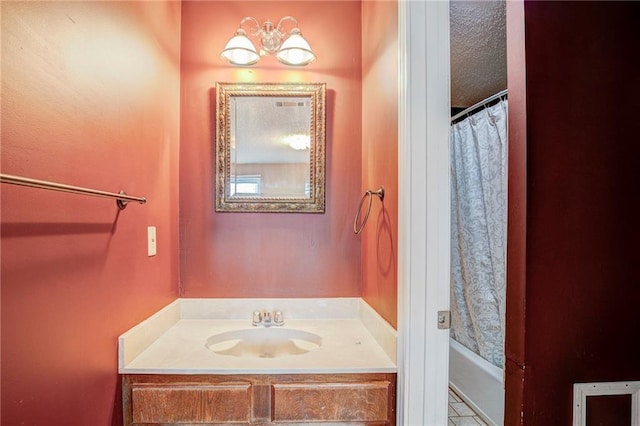 bathroom featuring a textured ceiling, a notable chandelier, shower / bath combo with shower curtain, and sink