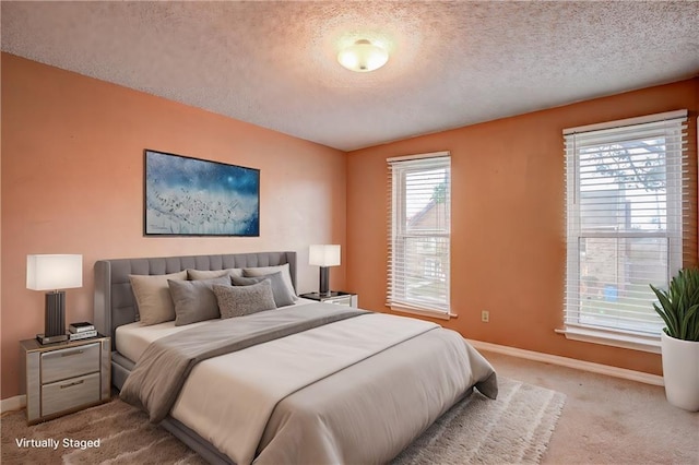 bedroom with light colored carpet, a textured ceiling, and multiple windows