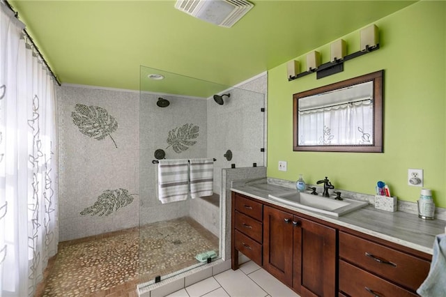 bathroom featuring tile patterned flooring, vanity, and a tile shower