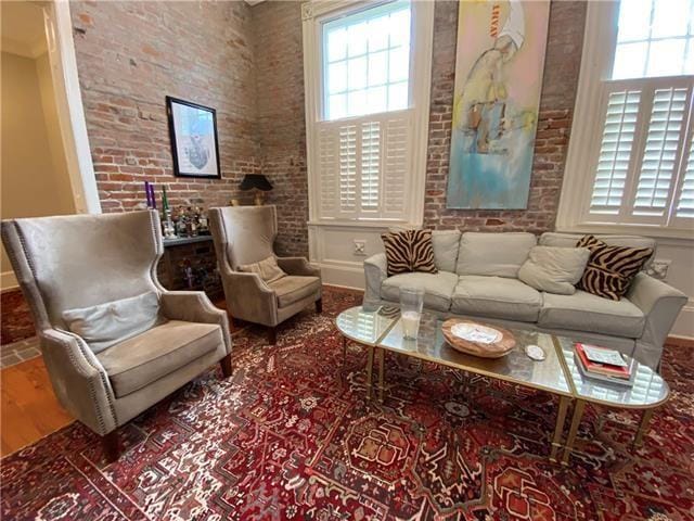 living room with wood-type flooring, brick wall, and a towering ceiling