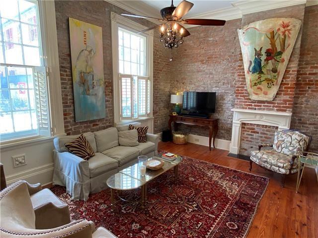 living room with ceiling fan, wood-type flooring, brick wall, and ornamental molding