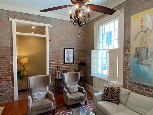 sitting room with crown molding, brick wall, and a chandelier