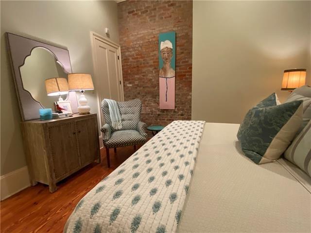 bedroom featuring hardwood / wood-style floors and brick wall