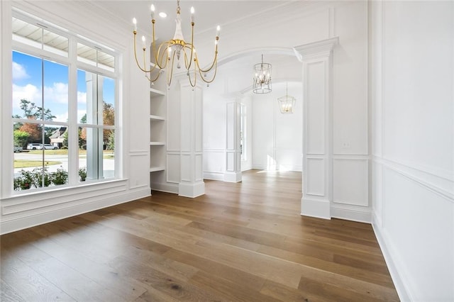 unfurnished dining area featuring plenty of natural light, dark wood-type flooring, built in features, and ornamental molding