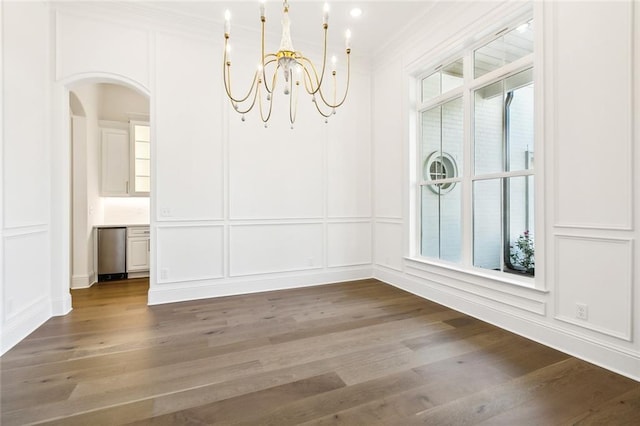 unfurnished dining area with a healthy amount of sunlight, dark wood-type flooring, and an inviting chandelier