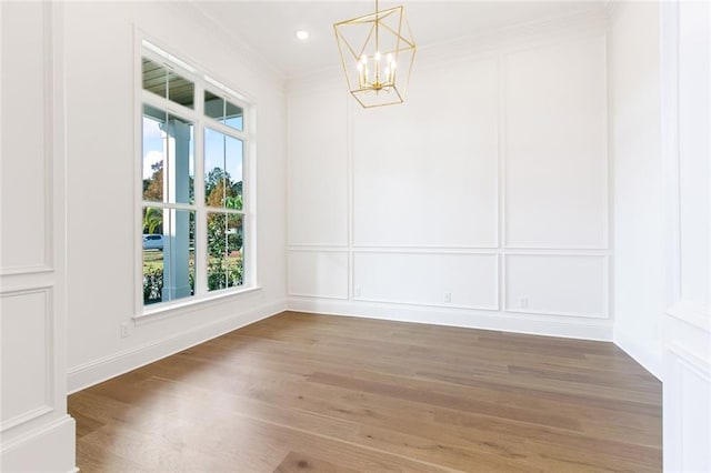 spare room featuring hardwood / wood-style flooring, a notable chandelier, and crown molding