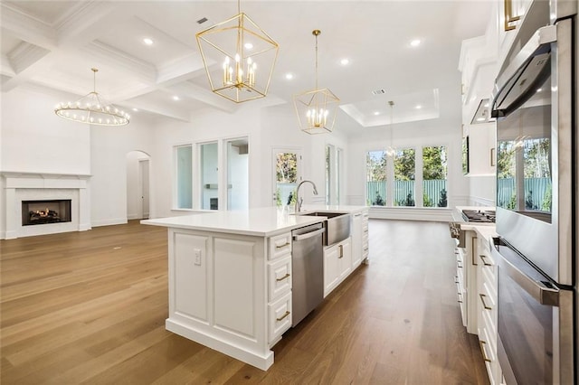 kitchen featuring pendant lighting, sink, hardwood / wood-style flooring, an island with sink, and appliances with stainless steel finishes