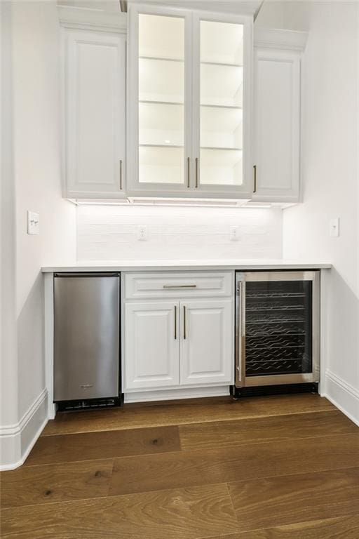 bar featuring fridge, white cabinetry, beverage cooler, and dark wood-type flooring