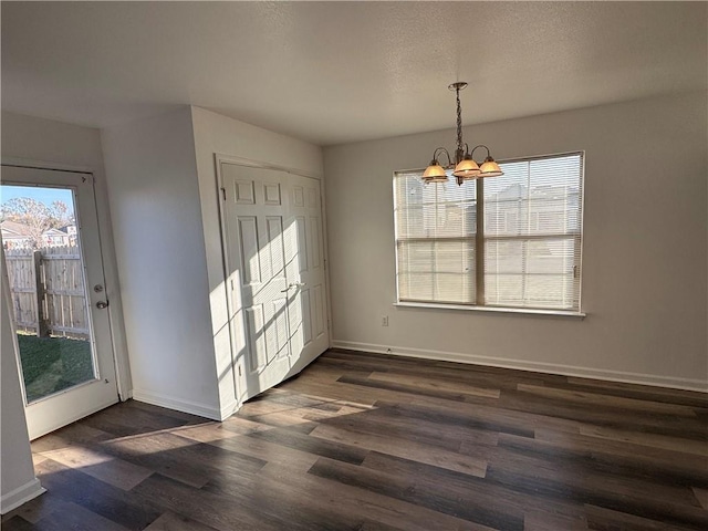 unfurnished dining area with a notable chandelier, dark wood-type flooring, and a wealth of natural light