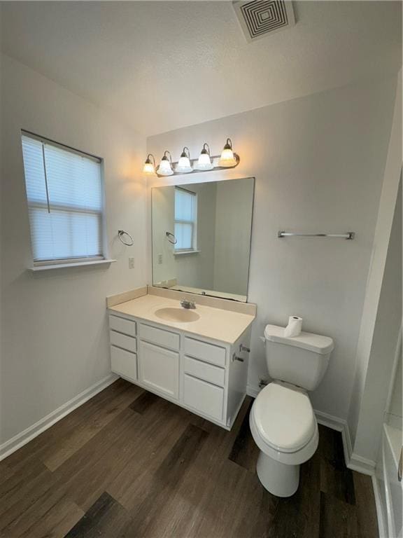 bathroom with a tub to relax in, vanity, wood-type flooring, and toilet