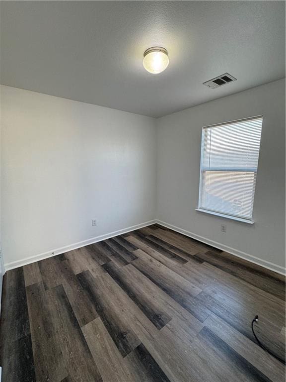 spare room with a textured ceiling and dark hardwood / wood-style floors