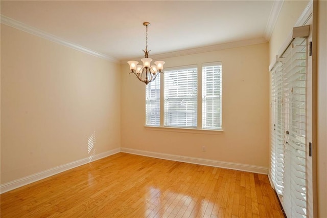 empty room with a chandelier, ornamental molding, and light wood-type flooring