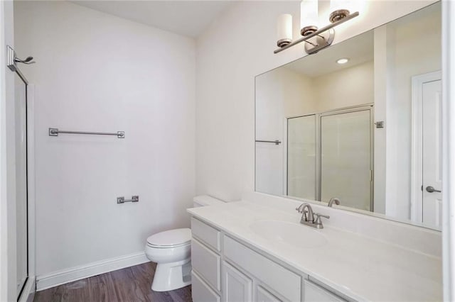 bathroom with hardwood / wood-style floors, vanity, toilet, and walk in shower