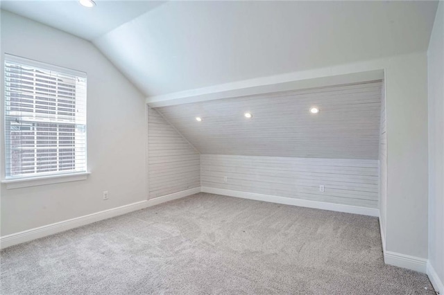 additional living space featuring light carpet, plenty of natural light, and lofted ceiling