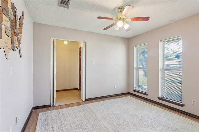 empty room featuring ceiling fan, hardwood / wood-style floors, and a textured ceiling