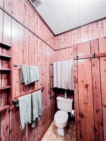 800 Anna St, Lafitte, LA 70067 - half bathroom featuring toilet and wood walls