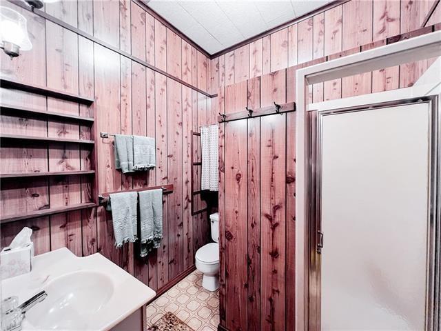 800 Anna St, Lafitte, LA 70067 - bathroom with wooden walls, toilet, tile patterned floors, vanity, and an enclosed shower
