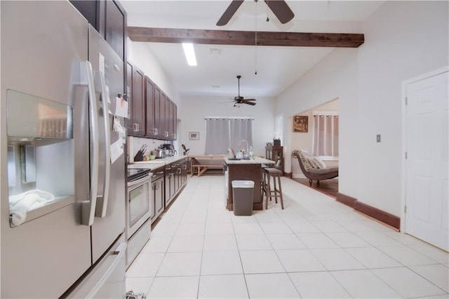 kitchen with a breakfast bar, white refrigerator with ice dispenser, electric range, a center island with sink, and beamed ceiling