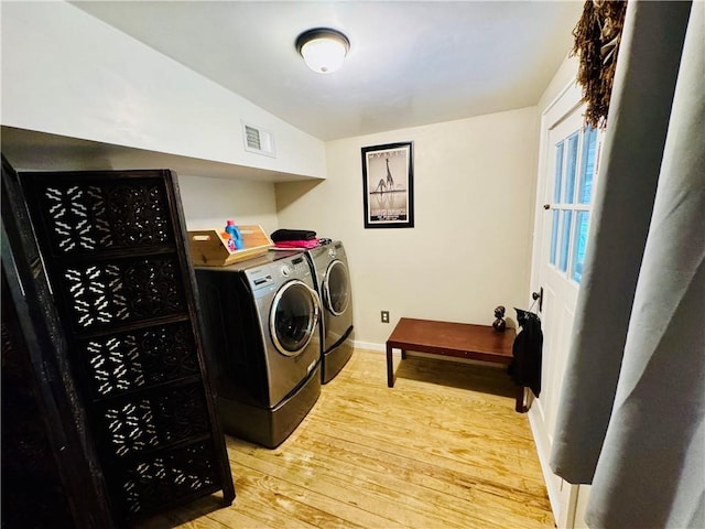 laundry area with washing machine and clothes dryer and light wood-type flooring