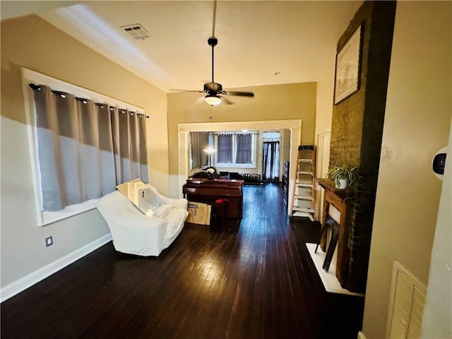 sitting room with ceiling fan and dark wood-type flooring