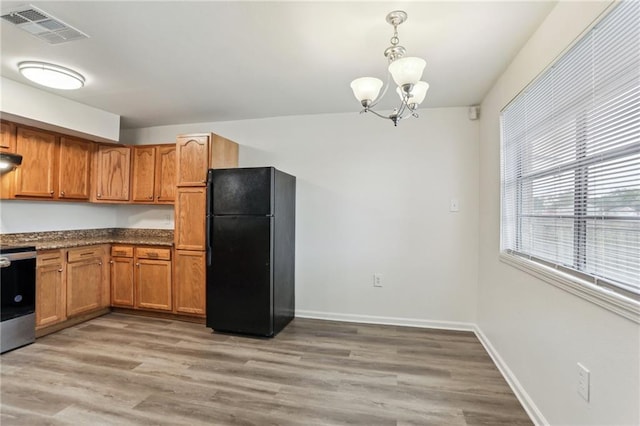 kitchen featuring light wood-type flooring, black fridge, a notable chandelier, stainless steel range oven, and hanging light fixtures