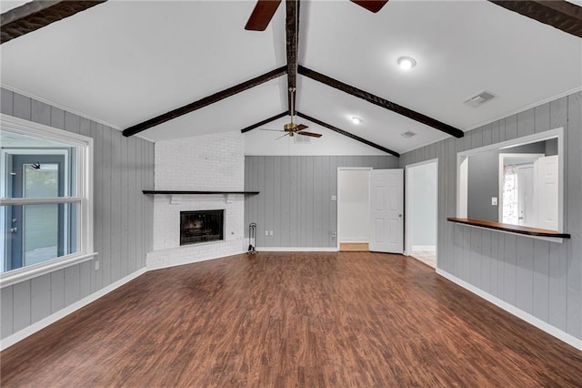 unfurnished living room featuring hardwood / wood-style floors, vaulted ceiling with beams, a brick fireplace, and wooden walls