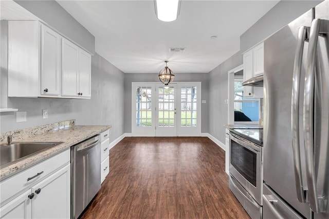 kitchen featuring light stone countertops, dark hardwood / wood-style flooring, decorative light fixtures, white cabinets, and appliances with stainless steel finishes