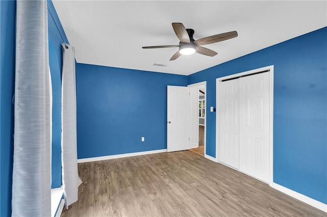 unfurnished bedroom featuring wood-type flooring, a closet, and ceiling fan