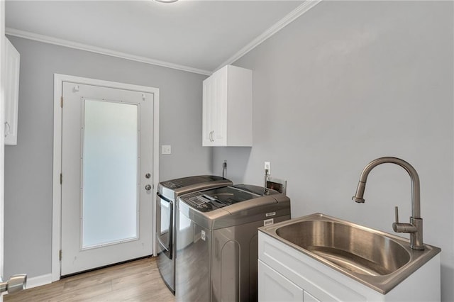 laundry area with cabinets, crown molding, sink, light wood-type flooring, and washing machine and clothes dryer